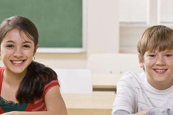 a pair of students in a classroom smiling at the camera