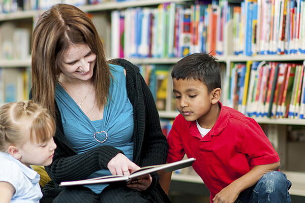 a teacher and students reading a book