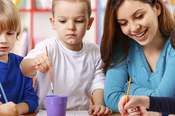 a group of kids painting with a teacher 