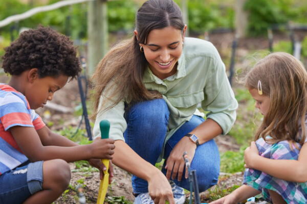 a teacher with students planting plants in a garden