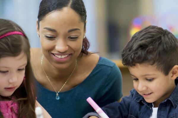 a teacher with 2 students working in a classroom