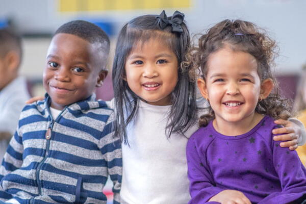 three kindergarden students smiling at the camera