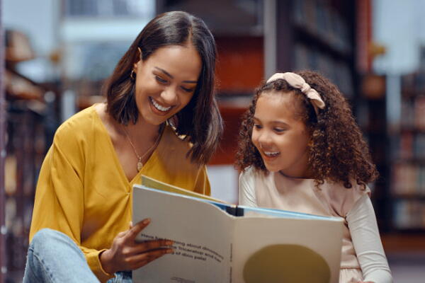 a person reading a book with a child inside a library