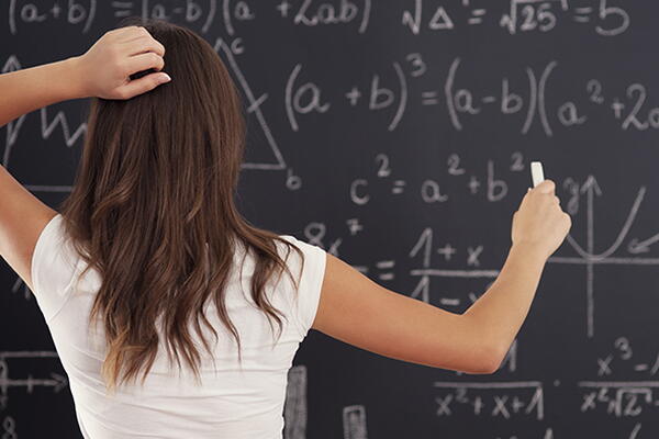 a student working on math equations on a chalkboard 