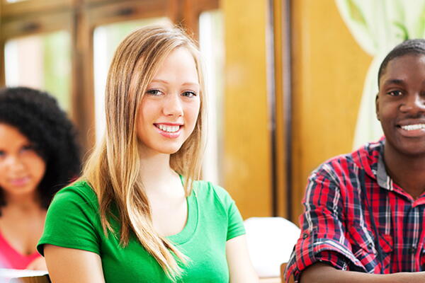 students smiling at the camera sitting in a classroom