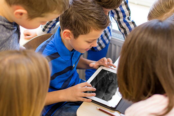 students in a circle watching a child with a tablet