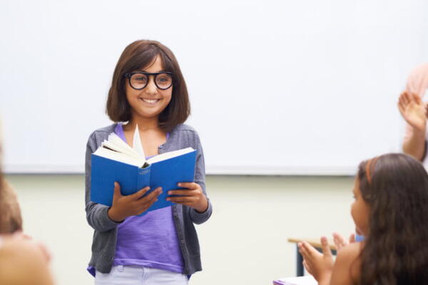 a student reading out a book to a class