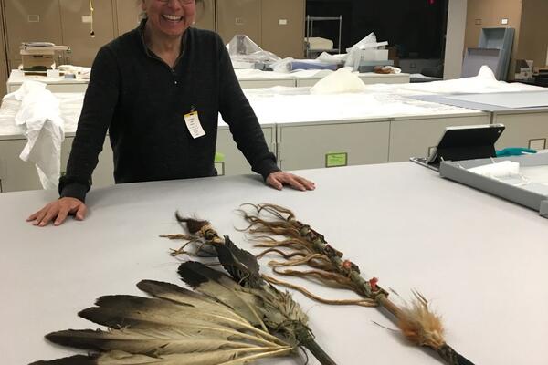 Dr. Alan Ojig Corbiere posing behind indigenous artifacts 