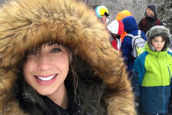 A woman outside in the winter with a large hood up 