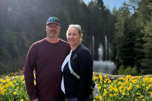 A couple standing in front of trees with flowers 