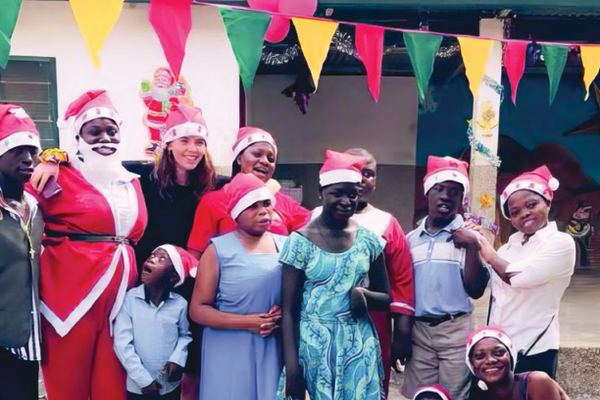 Laadi Salifu poses with her students outside wearing Santa hats.