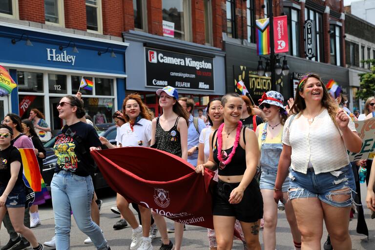 Students marching in a parade smiling at the audience