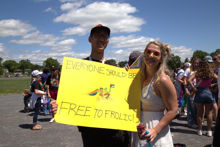 Two students holding up a sign with Frog and Toad on it that says everyone should be free to frolic