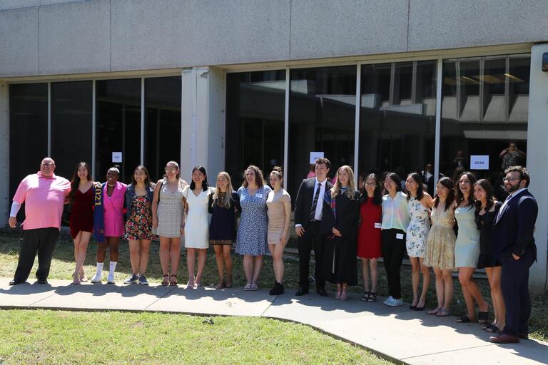 The graduates of 2021 stand in a row smiling.