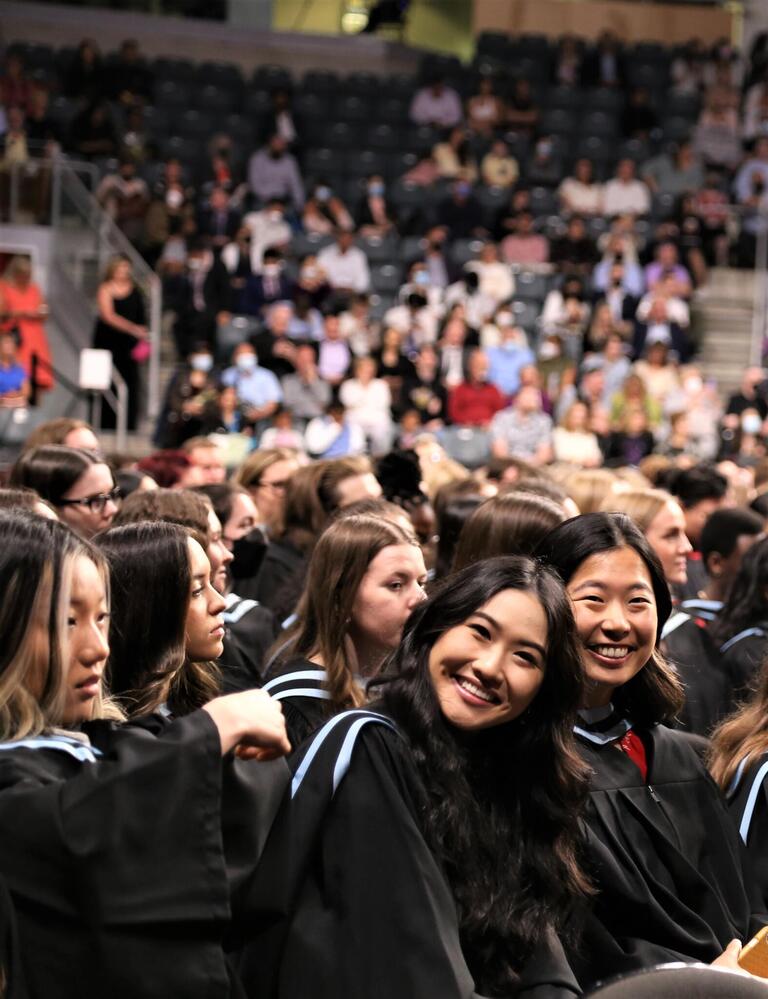 Two graduates seated beside each other smiling.