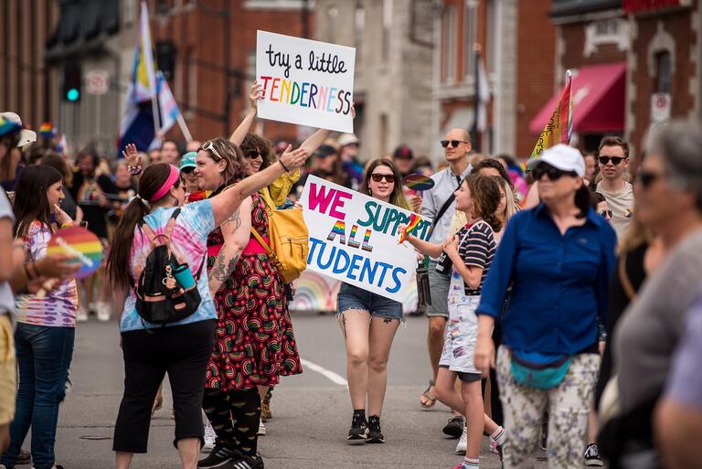 Students marching in a Pride Parade with signs that read Try a Little Tenderness and We Support All Students 