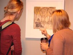 Two women looking at a painting.