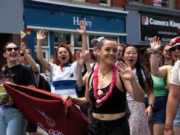 Students marching in Pride Parade with Faculty of Education Banner while waving
