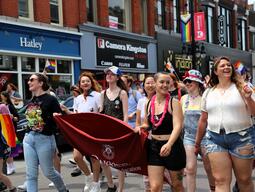 Students marching in a parade smiling at the audience