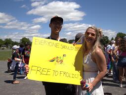 Two students holding up a sign with Frog and Toad on it that says everyone should be free to frolic