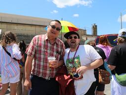 Two men look at the camera with rainbow outfits on