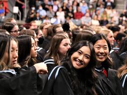 Two graduates seated beside each other smiling.