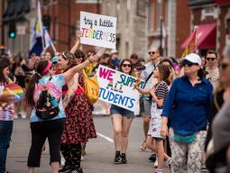 Students marching in a Pride Parade with signs that read Try a Little Tenderness and We Support All Students