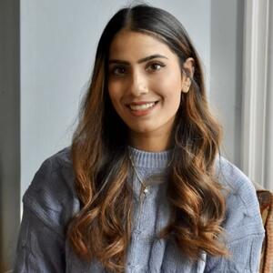 Tanya sits in a blue sweater smiling at the camera