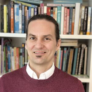 Jordan Shurr standing in front of a bookcase