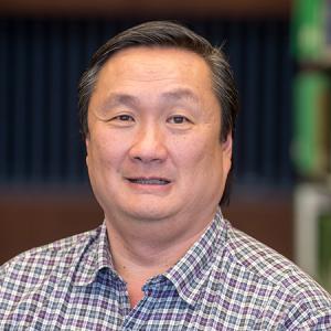Peter Chin smiling between bookcases in the library