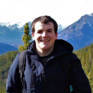 Michael Holden smiling in front of trees and mountains