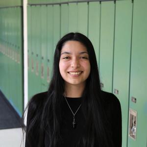 Maria smiles at the camera. She has long straight, black hair. She is wearing a black shirt and a necklace.