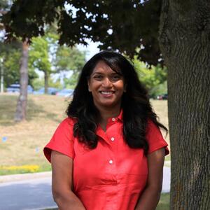 Thashika Pillay smiles outside next to a tree.