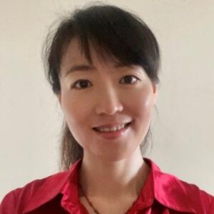 Raine Yuan smiles in front of a white wall wearing a red collared shirt.