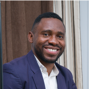 Paul Akpomuje smiles in a blue blazer inside.