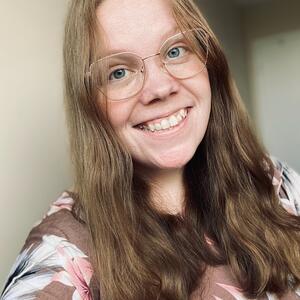 A woman with brown hair and glasses smiles at the camera