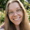 A woman with brown hair and glasses smiles at the camera