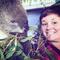 Nathalie smiles at the camera. she has short dark brown hair. She is standing very close to a koala