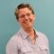 Karen Burkett standing in front of a light blue green wall and smiling 