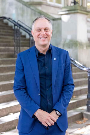 Eric Baumgartner is a blue suit standing in front of stone stairs