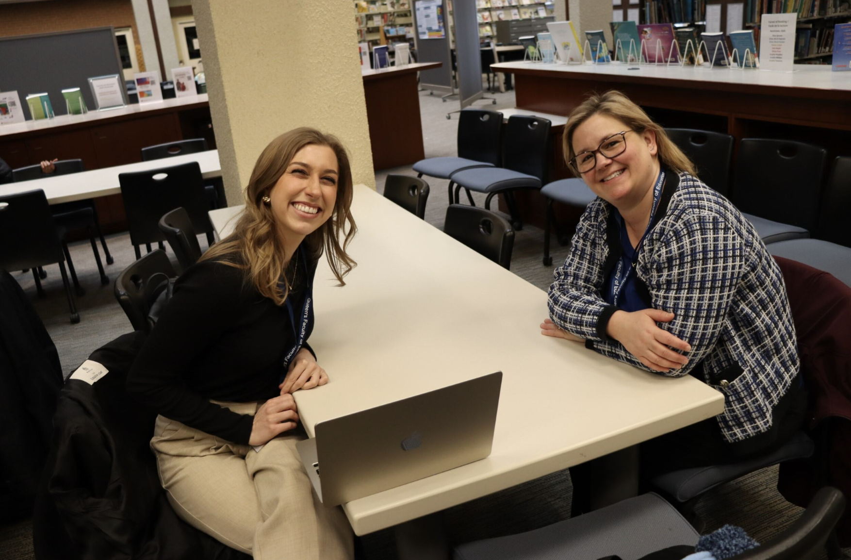 Erica Lewick and Natalie Soini smile while sitting at a table in the Education Library