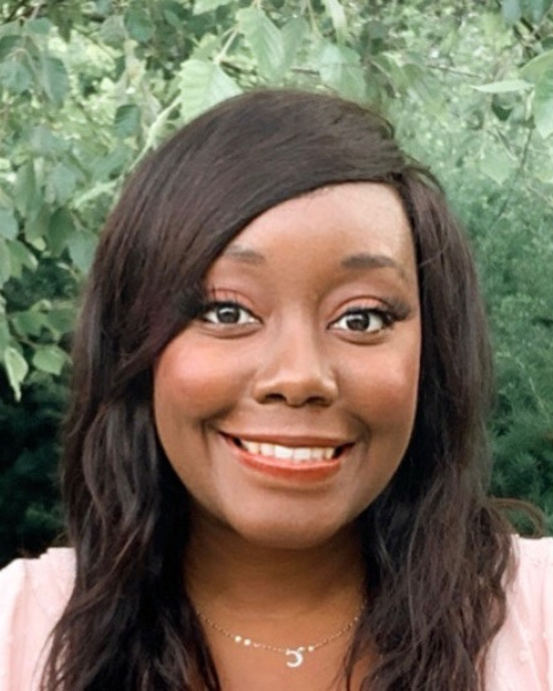 Nyasha smiles at the camera against a green background