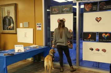 An attendee reads some literature with a service dog beside them