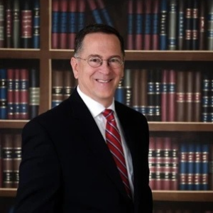 A man smiling in front of a bookcase
