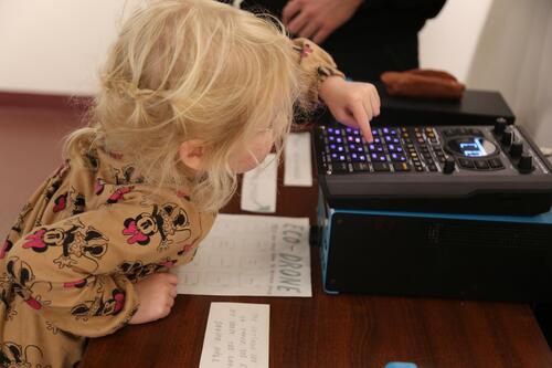 A child presses buttons on a synthesizer.