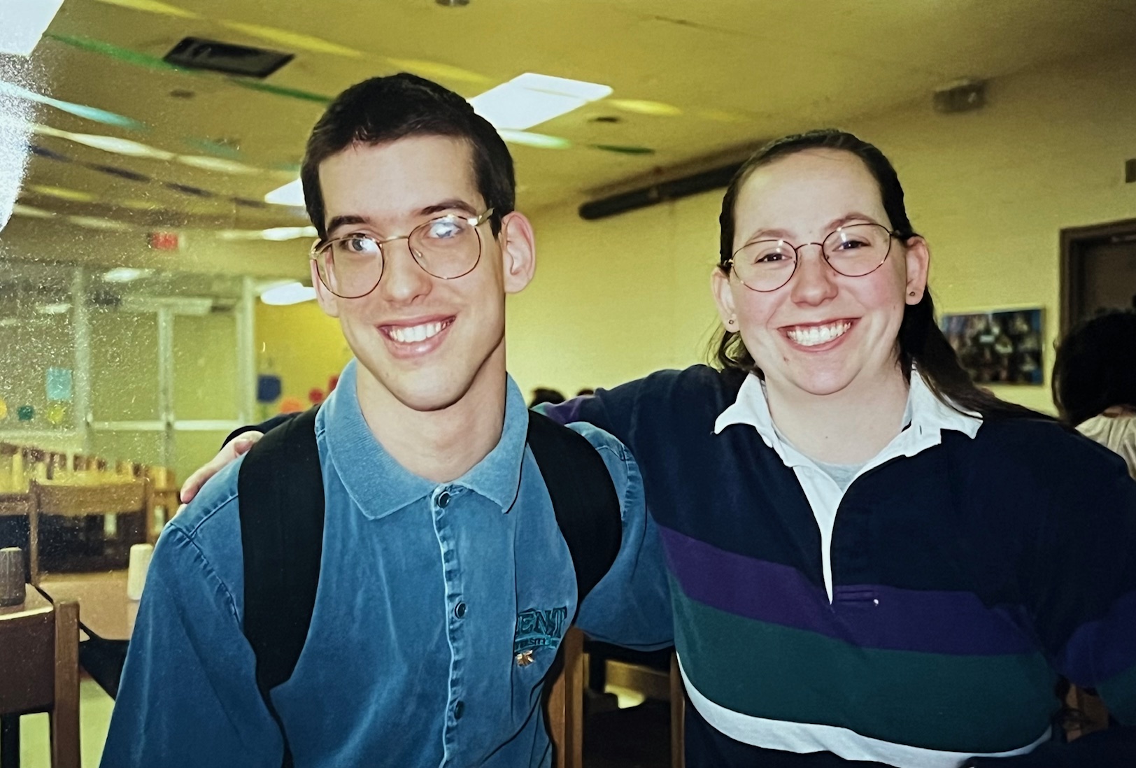 Two students pose in a film photo. They both wear glasses