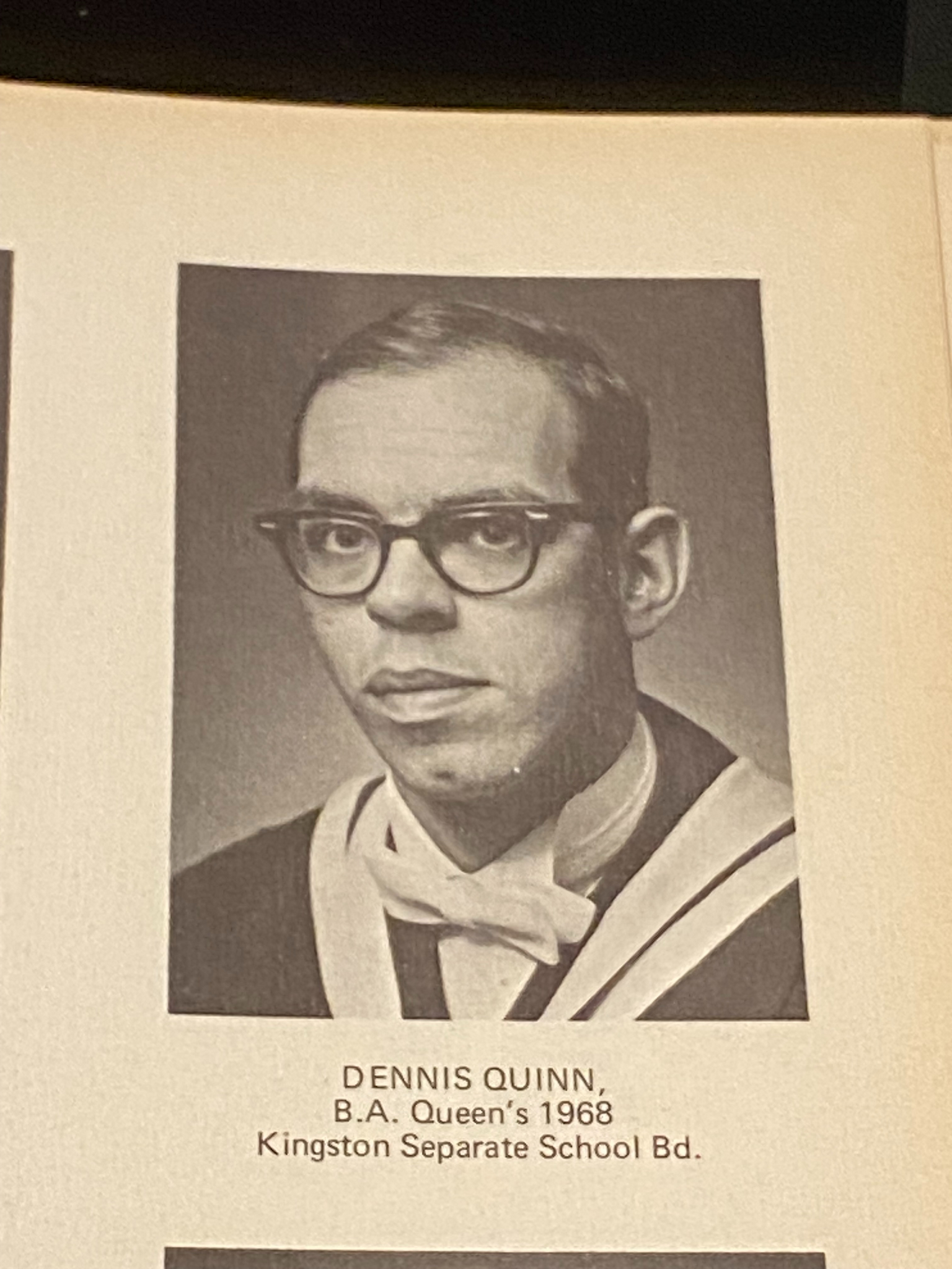 Dennis Quinn's yearbook photo where he wears glasses and his graduation information is written below the image.
