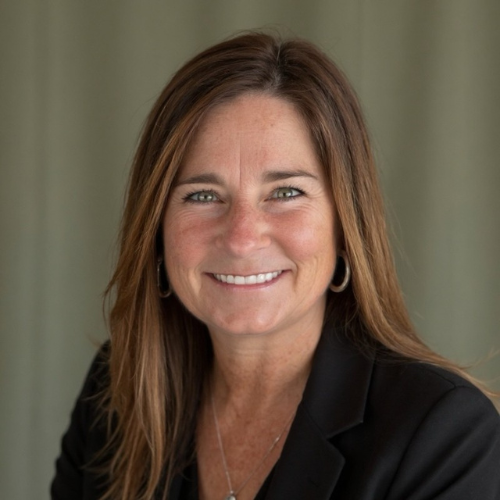 Jennifer McMaster smiles wearing a black shirt in front of a grey background.