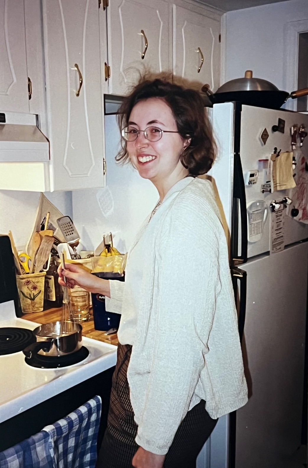 A student poses in a kitchen wearing glasses.
