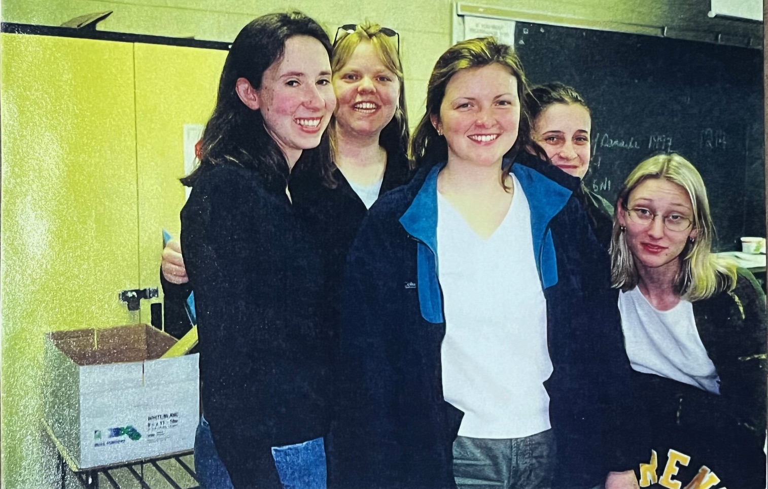 Five students pose in a classroom with yellow cabinets.